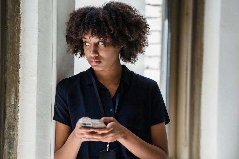 窓辺でスマホを持つ女性